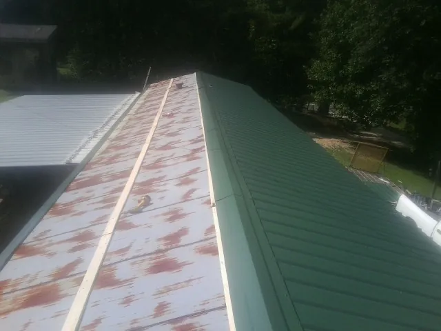Old rusted panels beside newly installed green metal roofing — Wind Damage Roof Repair by Roofing Brothers in Vincent