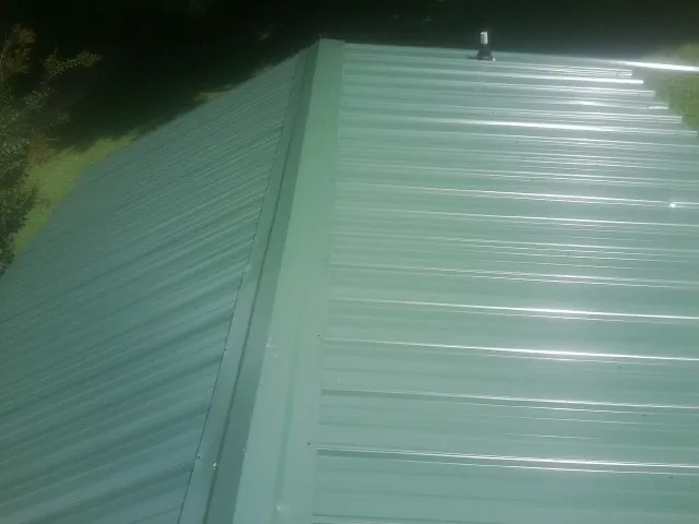 New green metal panels meeting at the ridge of a roof — Flat Roof Repair work by our crew in Vincent